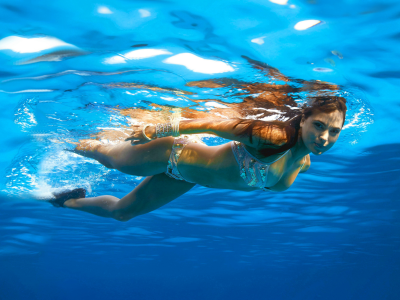 девушка, в купальнике, плавает под водой