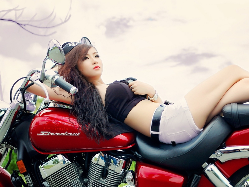 девушка, азиатка, лежит на мотоцикле