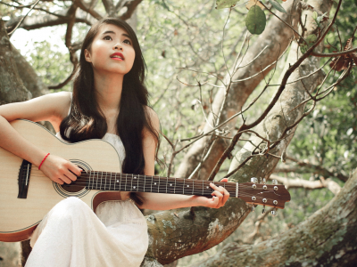 девушка, азиатка, играет на гитаре